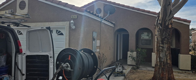Monster Rooter work van with the hydro jetting reel deployed outside a house